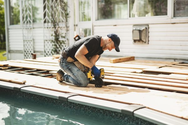 A Handyman worker making patio outside close to a pool