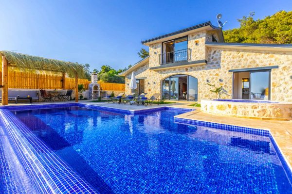 a-beautiful-stone-villa-with-a-stunning-blue-pool-and-lush-greenery.-19075388-scaled
